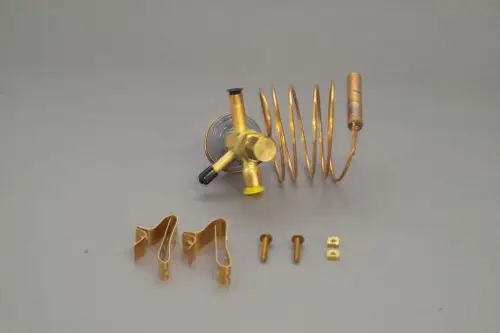 Brötje Expansionsventil in goldener Farbe mit spiralisiertem Rohr und Befestigungsteilen, auf grauem Hintergrund angeordnet.