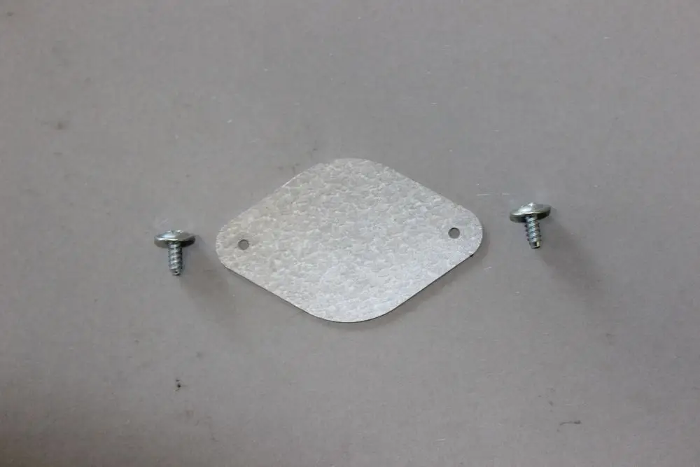 Brötje Verschlussplatte in flacher, ovale Form mit zwei Schrauben. Die Platte hat zwei Löcher zur Befestigung und eine strukturierte Oberfläche.