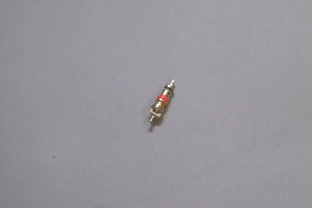 Brötje Innenteil eines Schraderventils in kompaktem Design, mit einem roten und einem silbernen Teil, auf grauem Untergrund abgebildet.