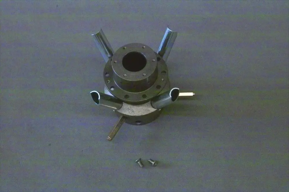 Gasverteiler mit mehreren Abgängen aus Metall, mittig hohl, auf dunklem Untergrund. Teile und Schrauben liegen separat daneben. Brötje Produkt erkennbar.