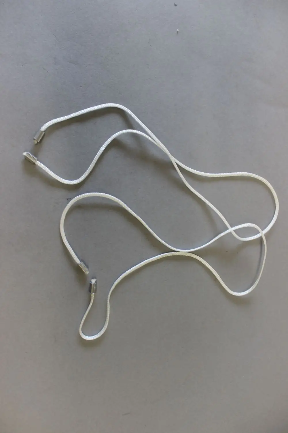 Zwei weiße, geflochtene Seile mit metallischen Enden, die für die Regelungsbox von Brötje verwendet werden. Leichte Krümmungen und Überlagerungen sind sichtbar.