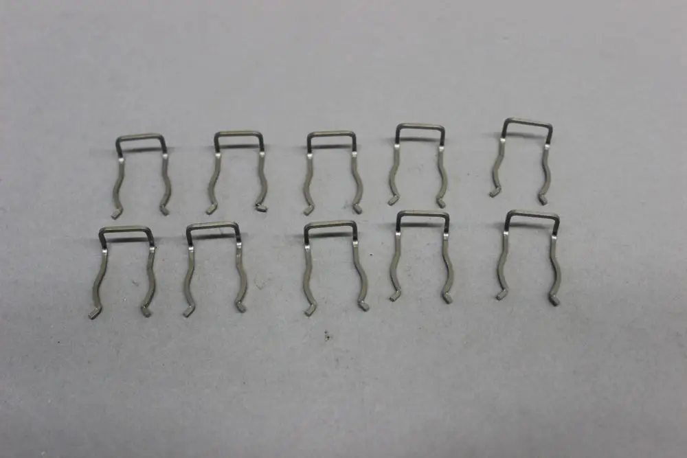 Mehrere brötje Arretierclips aus Metall, angeordnet in zwei Reihen, vor grauem Hintergrund. Die Clips haben eine U-Form und sind für die Befestigung von Sicherheitsventilen konzipiert.