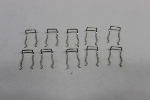 Mehrere brötje Arretierclips aus Metall, angeordnet in zwei Reihen, vor grauem Hintergrund. Die Clips haben eine U-Form und sind für die Befestigung von Sicherheitsventilen konzipiert.