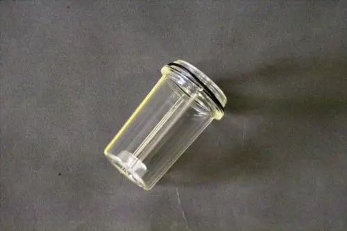 Transparente Glasdose mit schwarzem Deckel und Dichtungsring. Die Dose hat eine zylindrische Form und könnte Teil eines Brötje-Systems sein.