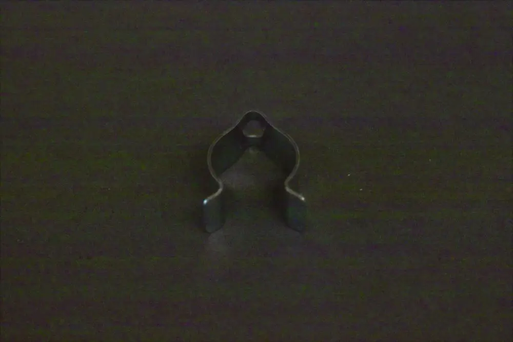 Fühlerclip von Brötje, aus Metall, mit einer offenen, geschwungenen Form und zwei seitlichen Halterungen. Auf schwarzem Untergrund präsentiert.