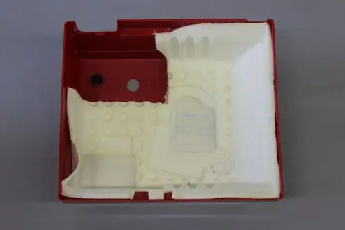 Rote Kunststoffhaube mit einer schaumstoffartigen Innenschicht, die für die Marke Brötje gestaltet ist. Die Oberseite weist zwei Ausschnitte auf.