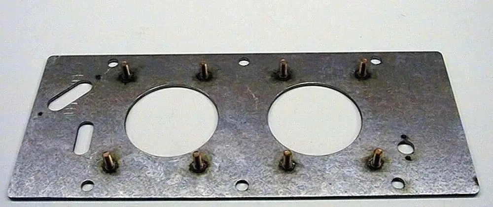 Metallplatte mit zwei runden Ausschnitten und mehreren Befestigungsbolzen, möglicherweise Teil eines Brötje Heizsystems.