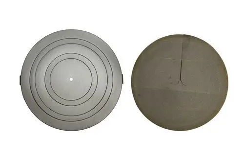 Zwei runde Isolierdeckel, einer mit konzentrischen Ringen in Grau, der andere mit einer glatten Oberfläche in Dunkelgrau, möglicherweise von der Marke Brötje.