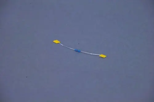 Brötje Widerstand mit blauer Wicklung und gelben Anschlussflächen, auf grauem Hintergrund.