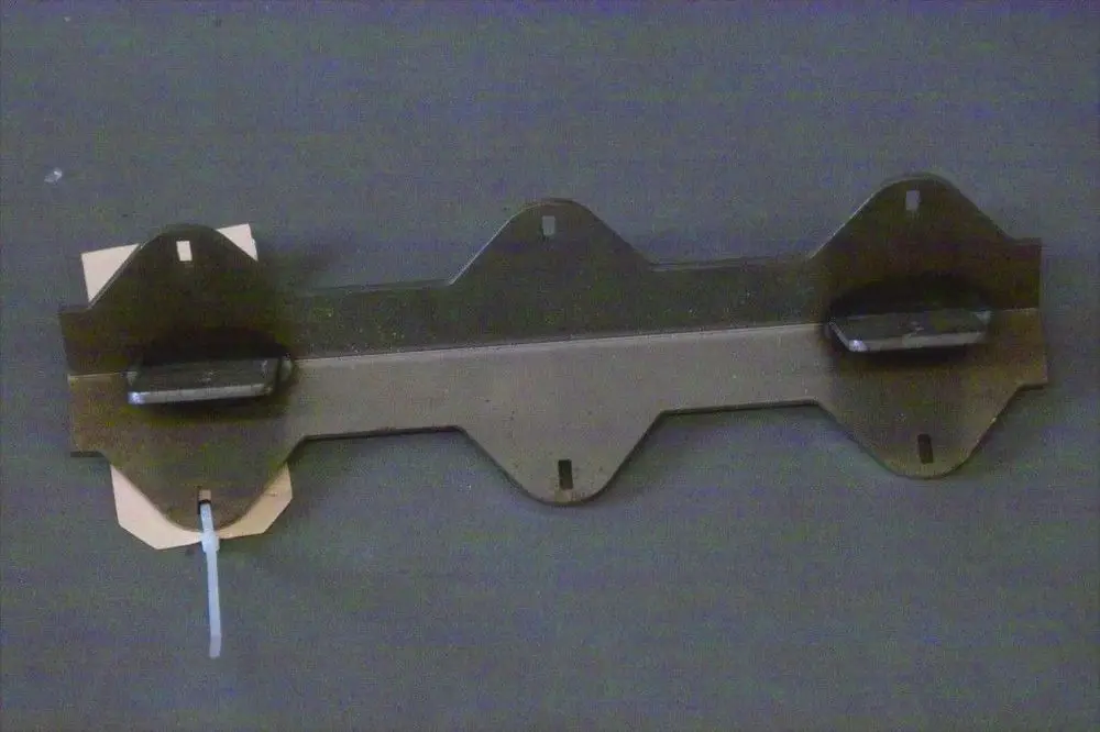 Brötje Reinigungswippe in metallischer Ausführung mit Halterungen und Befestigungslöchern, auf grauem Hintergrund, flach liegend.