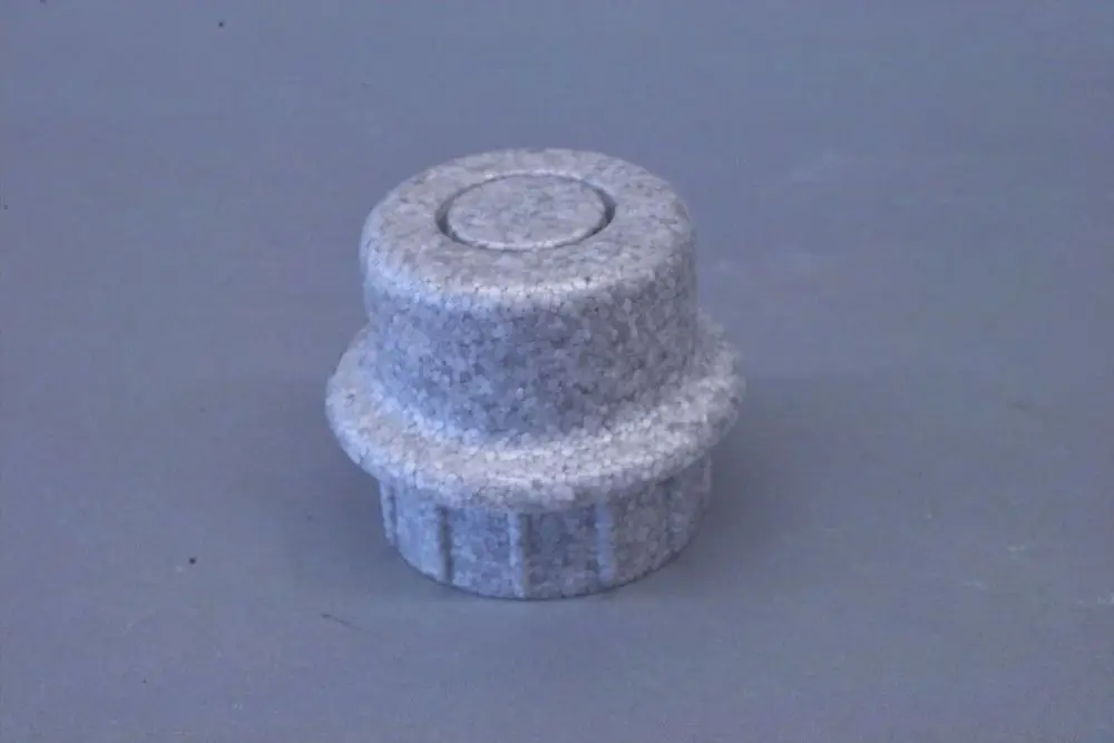 Grauer Stopfen, wahrscheinlich aus einem leichten Material, mit gerippter Unterseite und glatter Oberseite, von der Marke Brötje.