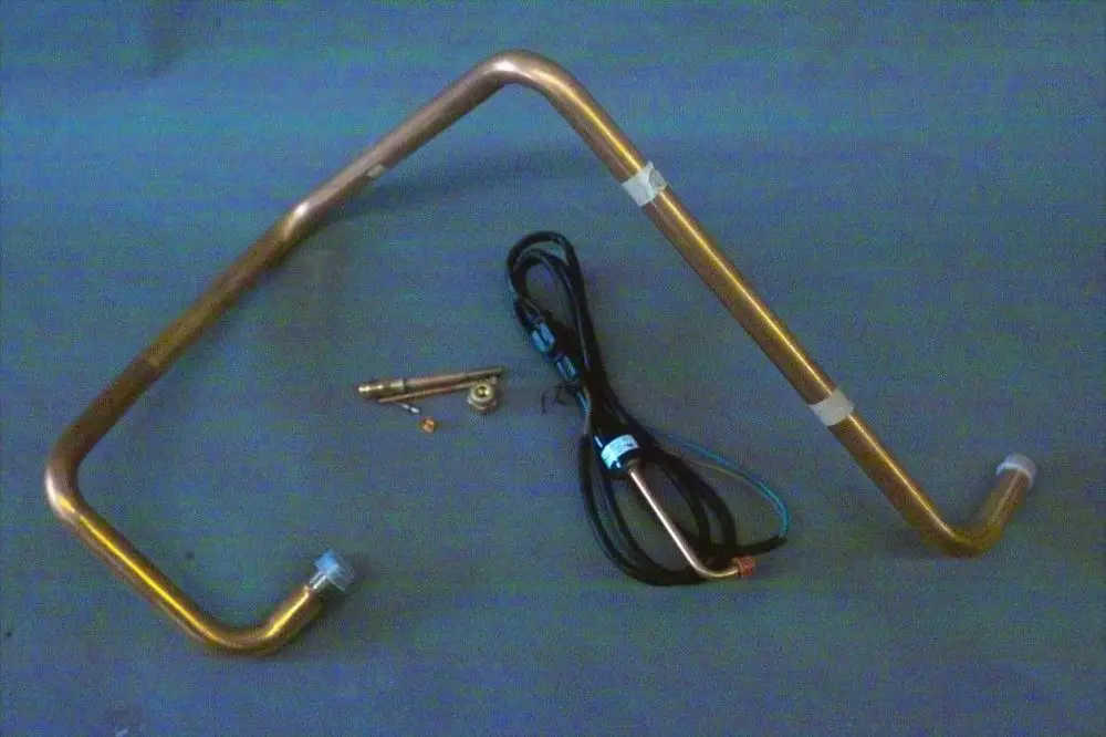 Brötje Sauggasleitung, in gebogener Form, aus Metall, mit Anschlussstücken und elektrischen Leitungen, auf grauem Untergrund platziert.