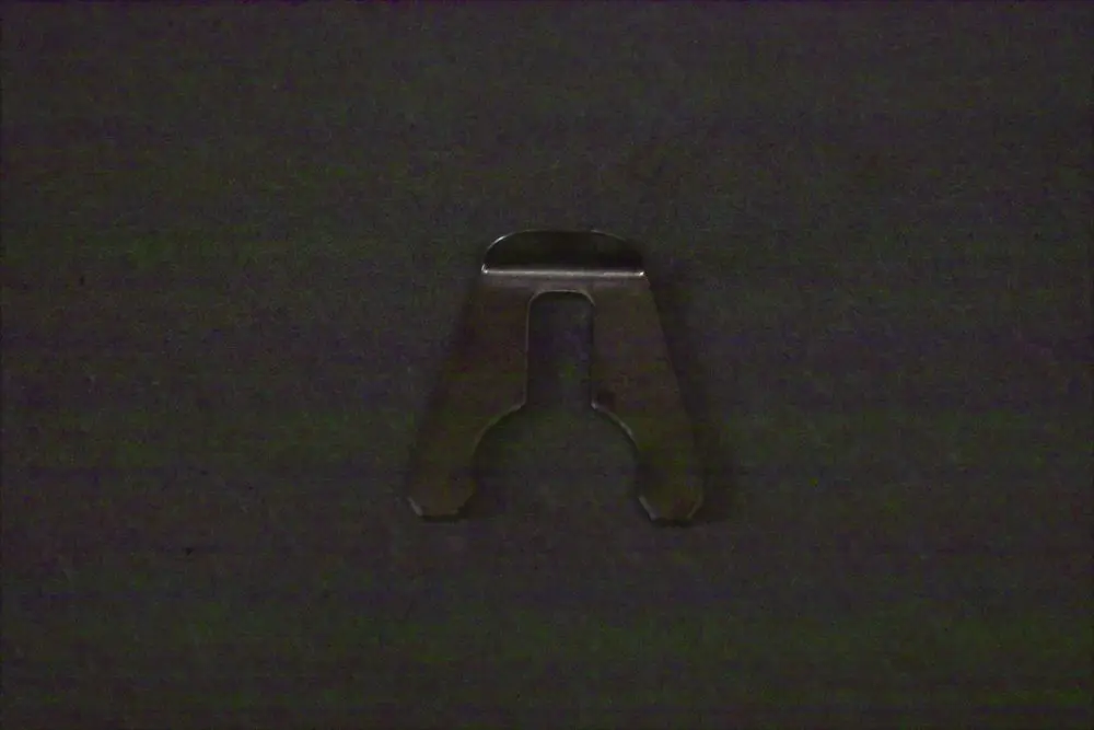 Befestigungsclip aus Metall, geformt mit einer Öffnung und zwei seitlichen Einkerbungen. Ergänzungsteil von Brötje, geeignet für einen Durchflusssensor.