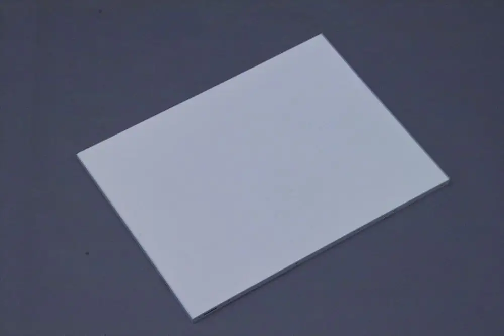 Weißes rechteckiges Plattenelement auf einem grauen Hintergrund, möglicherweise als Bauteil oder Abdeckung von Brötje-Produkten verwendet.