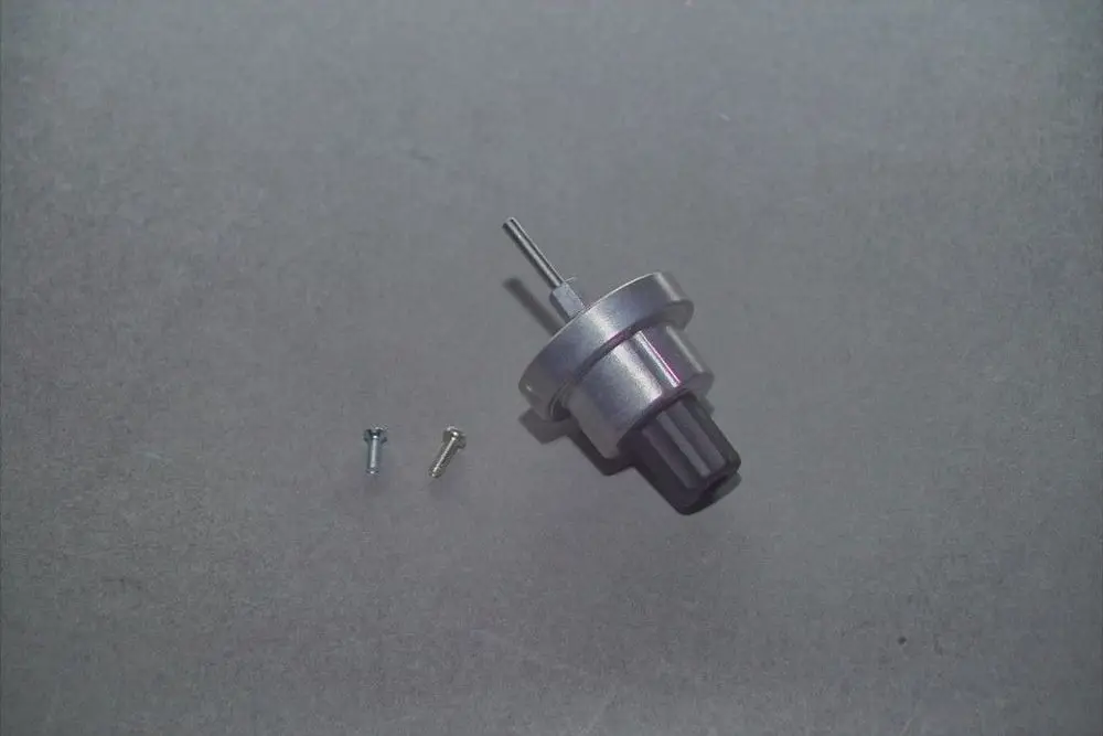 Brötje Hydraulikkopf in Metalloptik mit einem schlanken Stift und zwei Schrauben. Der Kopf hat einen flachen Boden und eine Öffnung oben.