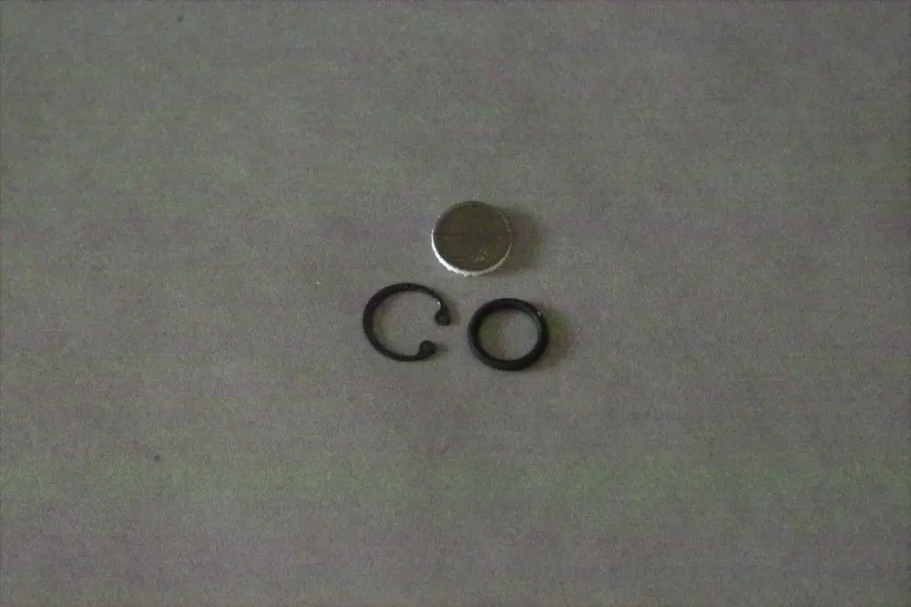 Brötje Zubehörteile auf grauem Untergrund: eine runde metallische Scheibe und zwei schwarze Ringe in unterschiedlichen Formen.