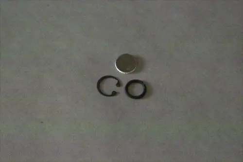 Brötje Zubehörteile auf grauem Untergrund: eine runde metallische Scheibe und zwei schwarze Ringe in unterschiedlichen Formen.