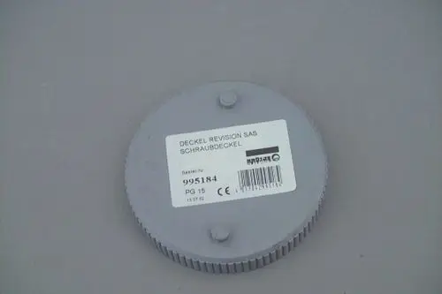Grauer runder Deckel mit Schraubmechanismus und Etikett. Auf der Oberfläche sind diese Details zu sehen: Produktnummer, Barcode und Sicherheitszeichen. Markierung für Brötje.
