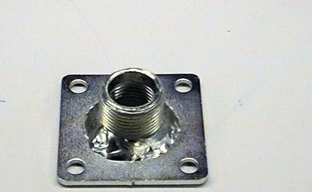 Brötje Düsenhalter aus Metall mit einem kegelförmigen Gewindeabschluss und vier Befestigungslöchern auf einer quadratischen Grundplatte.