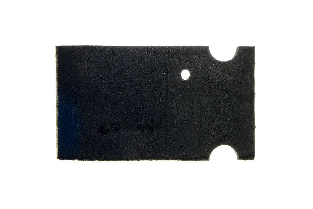 Schwarzes Stück Isoliermaterial mit zwei Ausschnitten und Löchern, möglicherweise für Rohrisolierung. Produkte von Brötje sind für Heizungsanwendungen gedacht.