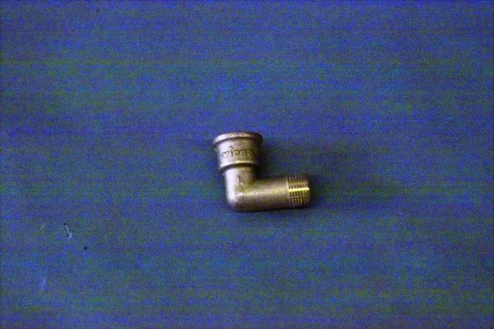 Brötje Winkelstück aus Metall mit einer geknickten Form und Gewinde, auf einem blauen Untergrund platziert.