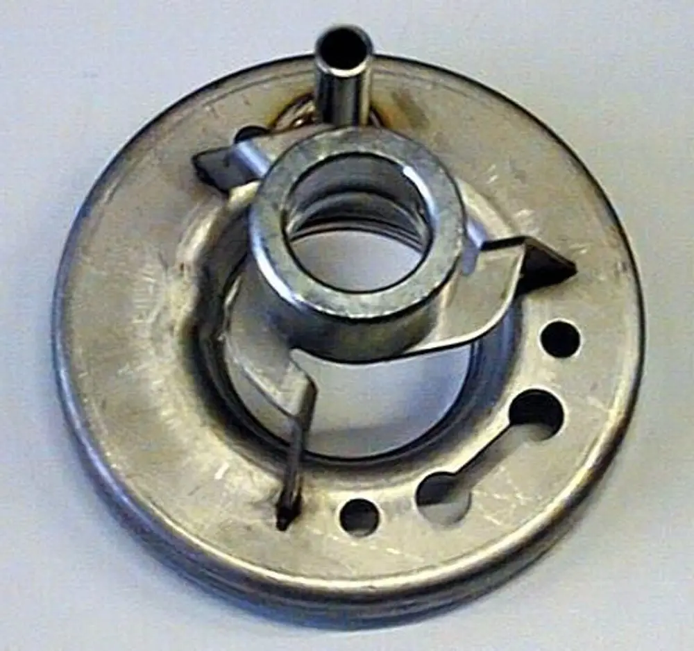 Brötje Mischeinheit, metallisches Bauteil mit einem zentralen Öffnungsbereich und mehreren Löchern, etwas gewinkelt mit einer kleinen Rohrverbindung.