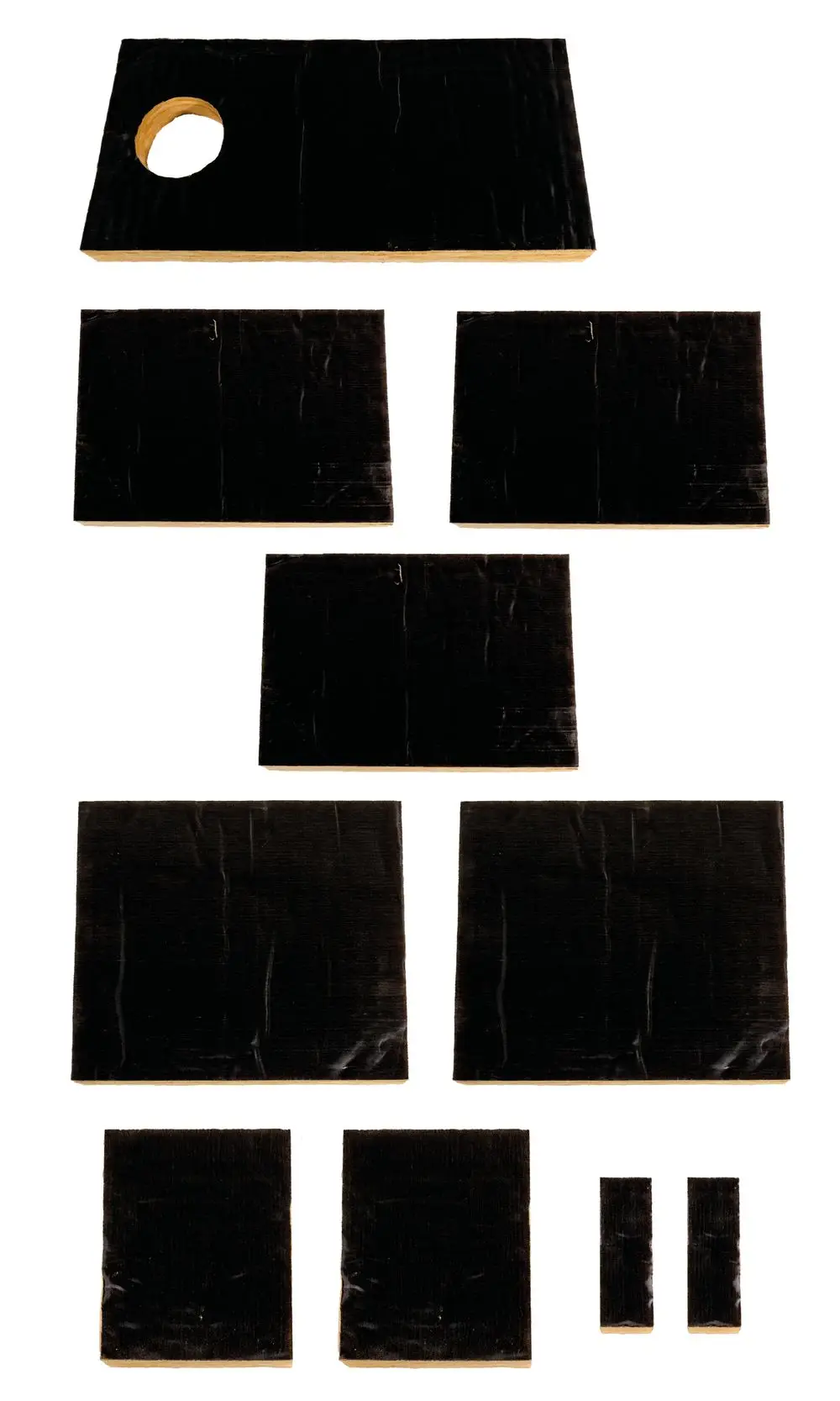 Set aus mehreren matten schwarzen Platten mit unterschiedlichen Größen und einem Element mit einem Loch, möglicherweise für Isolations- oder Dämmzwecke, gefertigt von Brötje.
