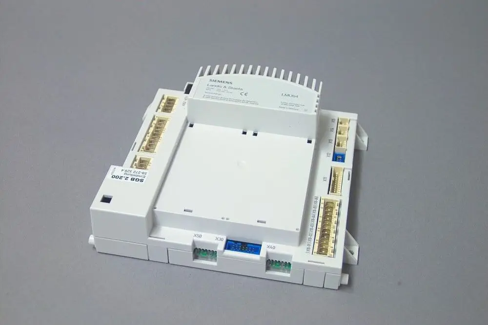 Weißes elektrisches Steuergerät mit Anschlussklemmen auf mehreren Seiten. Markierung und Typenbezeichnungen sind sichtbar. Dient zur Regelung von Heizsystemen von Brötje.