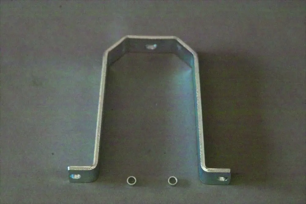 Brötje Halter in U-Form aus Metall, mit zwei Löchern an der Oberseite und zwei kleinen Ringen auf der Unterseite, auf grauem Hintergrund.