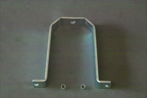 Brötje Halter in U-Form aus Metall, mit zwei Löchern an der Oberseite und zwei kleinen Ringen auf der Unterseite, auf grauem Hintergrund.
