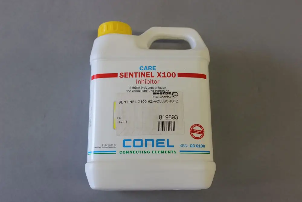 Weißer Kunststoffbehälter mit gelbem Deckel, beschriftet mit Brötje Sentinel X100 Inhibitor. Sicherheits- und Anwendungshinweise auf dem Etikett sichtbar.