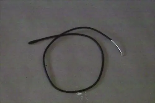 Schwarzes Kabel mit einem silbernen Ende, möglicherweise ein Temperaturfühler von Brötje, liegt auf einer grauen Oberfläche.