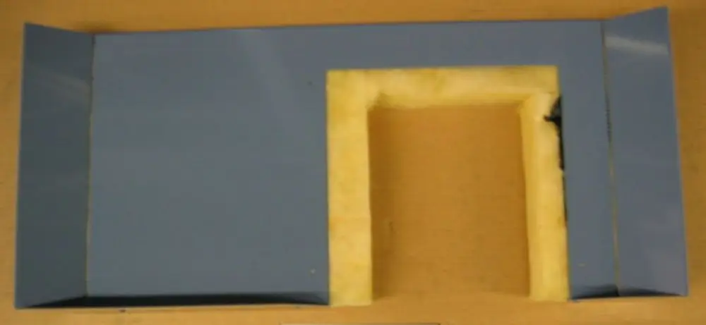 Brötje Verkleidungsrückwand in blau mit einer eingerahmten Öffnung in der Mitte, umgeben von Dämmmaterial. Hergestellt für eine Heizungsanwendung.