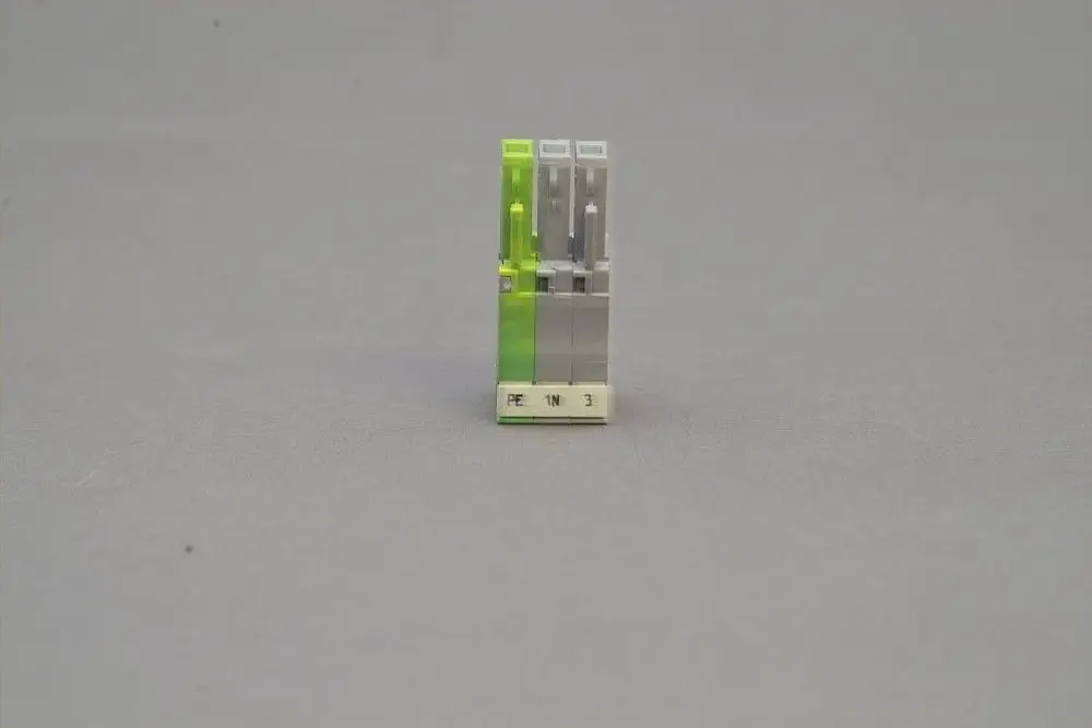 Brötje Stecker mit drei Polen in grauer und grüner Ausführung, auf weißem Untergrund. Die Anschlussbezeichnungen für PE, N und 3 sind sichtbar.