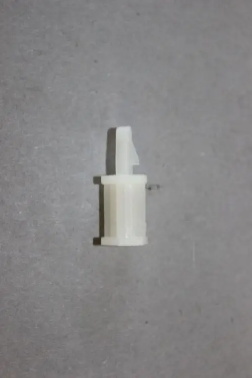 Kunststoffhalter von Brötje, zylindrische Form mit einem seitlichen Clip, auf grauem Untergrund.