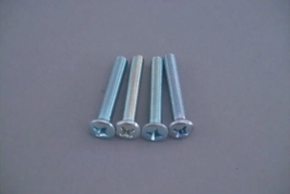 Brötje Schrauben-Set aus vier blauen Schrauben mit Kreuzschlitzkopf auf grauem Untergrund, angeordnet in einer Reihe.
