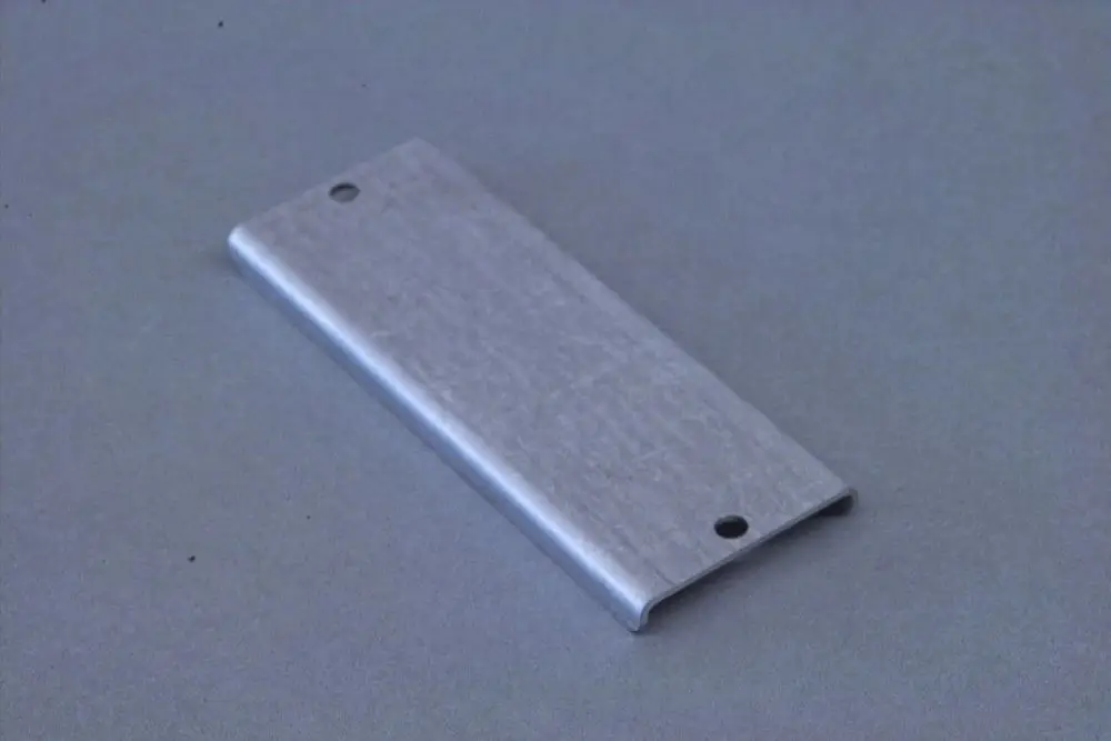 Metallene Abdeckung oder Platte mit zwei Löchern, möglicherweise von Brötje, auf grauem Hintergrund. Funktion und Einsatzbereich sind nicht konkret erkennbar.