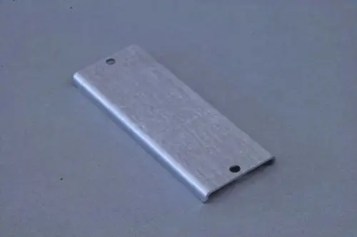 Metallene Abdeckung oder Platte mit zwei Löchern, möglicherweise von Brötje, auf grauem Hintergrund. Funktion und Einsatzbereich sind nicht konkret erkennbar.
