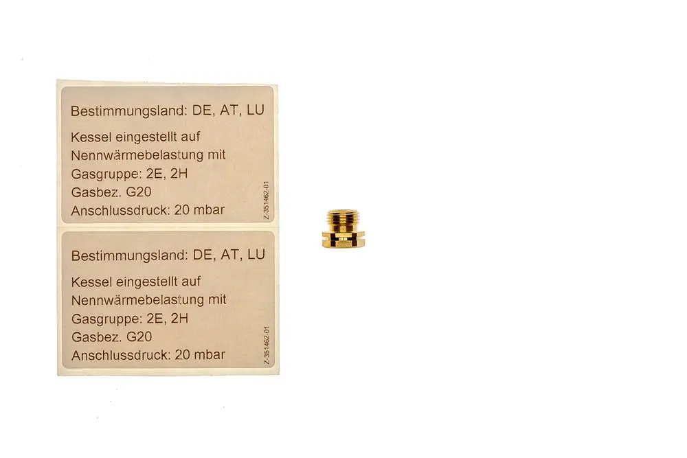 Zwei Informationsaufkleber mit technischen Angaben zur Gaseinstellung für ein Brötje-Gerät sowie ein Messingadapter in der Mitte des Bildes.