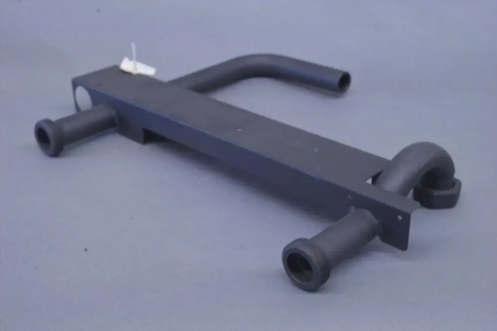 Brötje-Rohrkomponente mit zwei gekrümmten Enden und einer seitlichen Verbindung, in schwarzem Material. Dreidimensionales Design ohne erkennbare Maße.