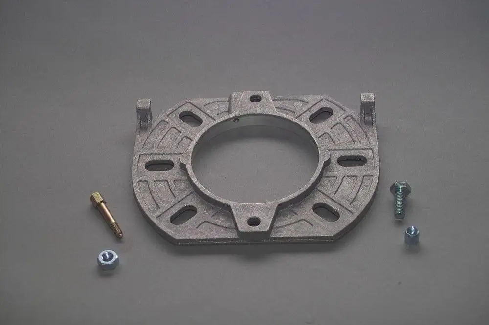Brötje Kesselflansch aus Metall mit einem zentralen Loch und mehreren Montageöffnungen, umgeben von zwei Schrauben und einer zusätzlichen Verschraubung.