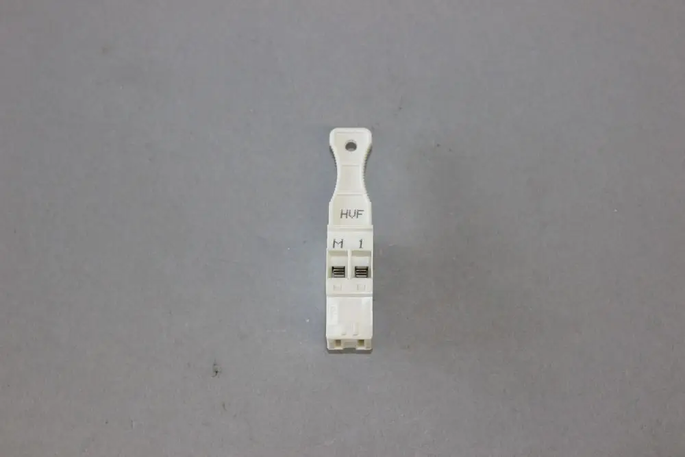 Brötje Stecker in hellem Kunststoff, vertikal angeordnet, mit Anschlüssen und Beschriftung "HUF", "M" und "1" auf der Vorderseite.
