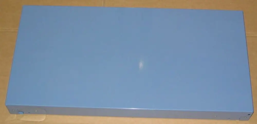 Blaues, rechteckiges Gehäuse von Brötje, flache Oberseite, ohne sichtbare Öffnungen oder Beschriftungen, auf einer braunen Kartonunterlage liegend.