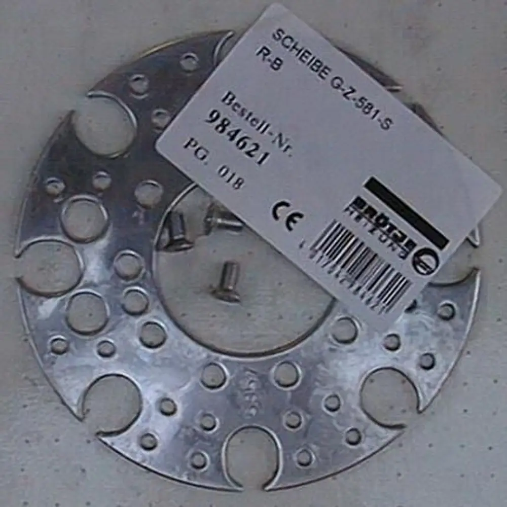 Metallische Scheibe mit mehreren Löchern und Ausschnitten, posiert mit Schrauben und einem Etikett. Brötje ist als Marke auf dem Etikett sichtbar.