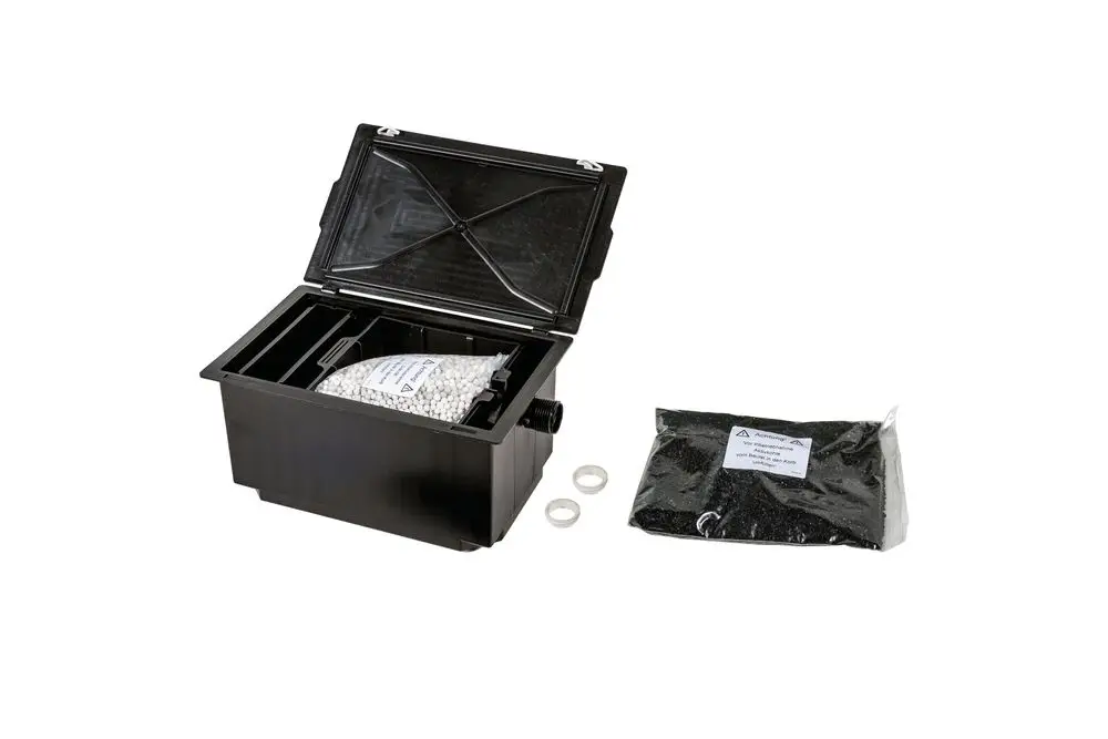 Brötje Box mit geöffnetem Deckel, gefüllt mit Granulat und einer zusätzlichen Tüte schwarzem Material, daneben zwei Dichtungsringen auf hellem Hintergrund.
