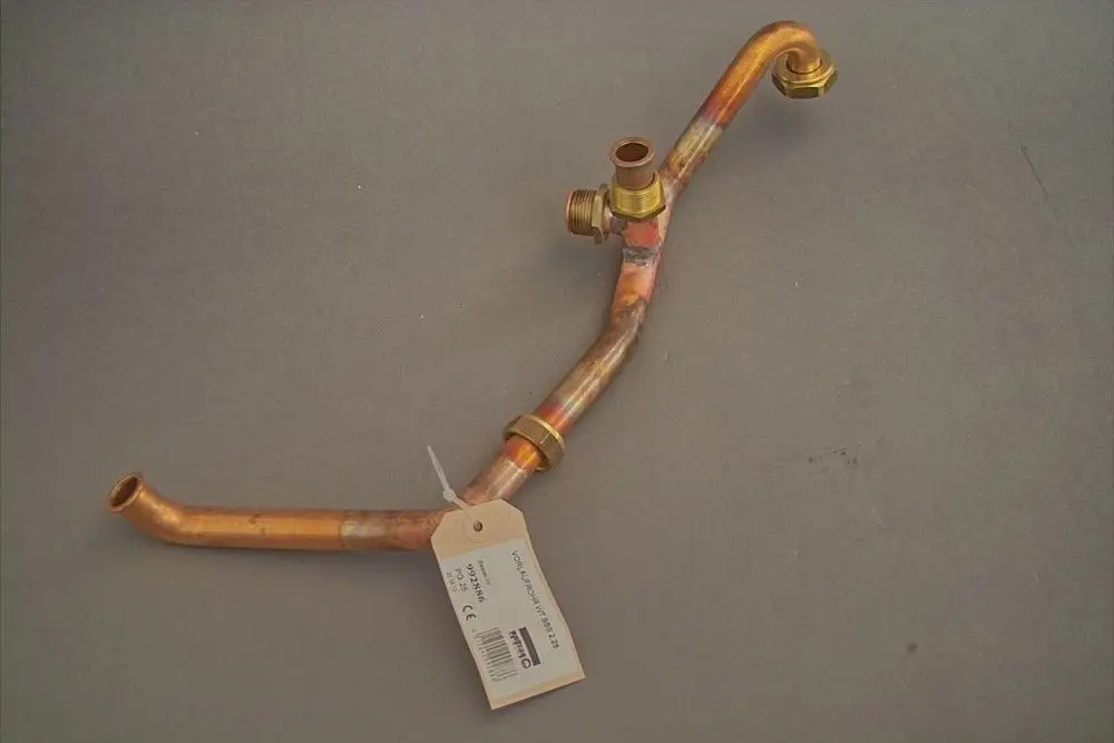 Kupfernes Rohr mit mehreren Biegungen und Anschlüssen, möglicherweise für Heizungsanwendungen, mit Etikett. Produkt von Brötje.