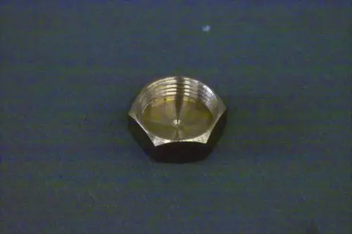 Metallene Kappe mit sechseckigem Profil und Innengewinde, liegend auf einem dunklen Untergrund. Es ist ein Produkt von Brötje.