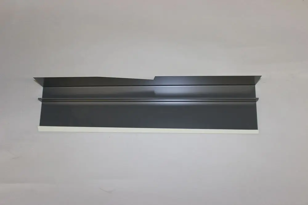 Brötje Verbindungselement in schwarzem Finish, flache Bauweise mit zwei parallelen Leisten und einer seitlichen Aussparung, auf grauem Hintergrund platziert.