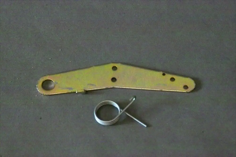 Brötje Hebel aus metallischem Material mit mehreren Löchern und einer Feder. Der Hebel hat eine ovale Öffnung an einem Ende und ist leicht gebogen.
