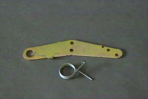 Brötje Hebel aus metallischem Material mit mehreren Löchern und einer Feder. Der Hebel hat eine ovale Öffnung an einem Ende und ist leicht gebogen.